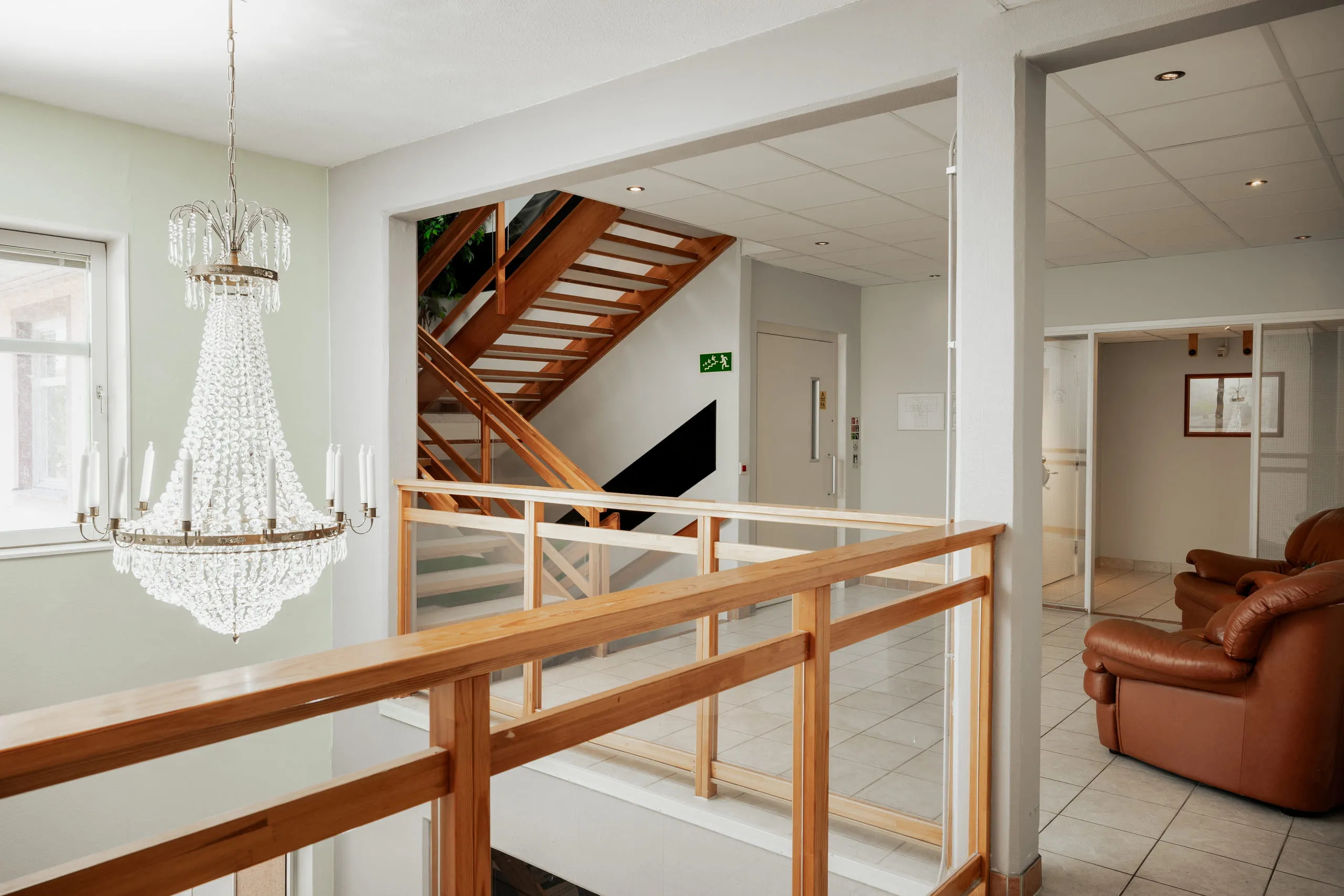 Trapphus med ljuskrona och trappräcke i ljust trä